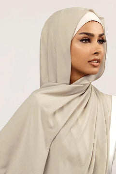 Georgette Hijab Online Pakistan, in pistachio gray color. A woman wearing it with white top looking her left.