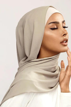 Georgette Hijab Online Pakistan, in pistachio grey color. A woman wearing it with white top looking her left.