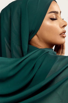 Georgette Hijab Online Pakistan, in peacock color . a women wearing it with white top looking her left.