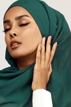 Hijab in peacock color . a women wearing it with white top looking her right.