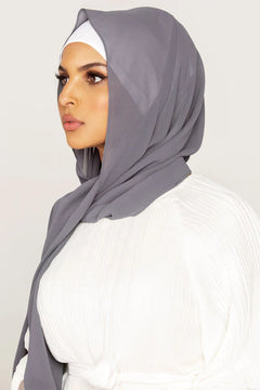 Georgette Hijab Online Pakistan, in smoke color . side profile of a woman wearing it with white top looking her straight.