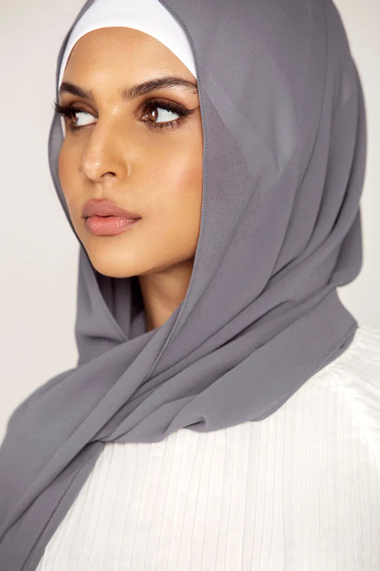 Georgette Hijab Online Pakistan, in smoke color. A woman wearing it with white top looking her right.