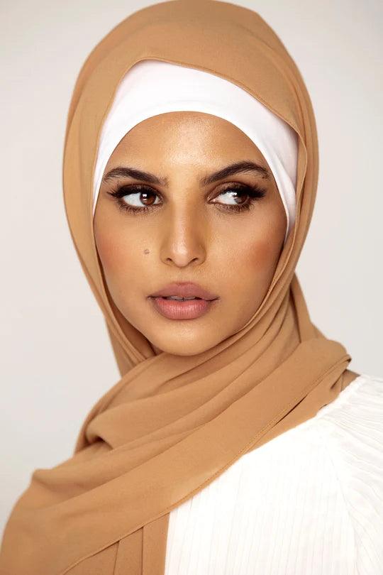 Georgette Hijab Online Pakistan, in golden brown color. A woman wearing it with white top looking her left.