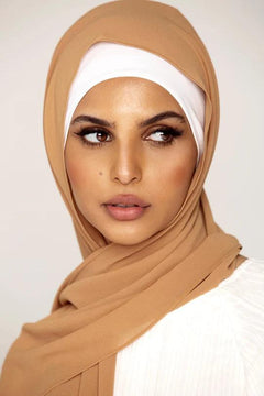 Georgette Hijab Online Pakistan, in golden brown color. A woman wearing it with white top looking her left.