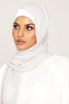 Georgette Hijab Online Pakistan, in light gray color. A woman wearing it with white top looking her right.