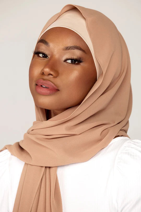 Georgette Hijab Online Pakistan, in soft beige color . a women wearing it with white top looking her right.