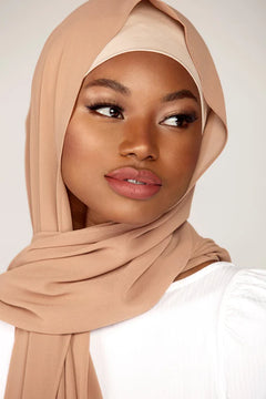 Georgette Hijab Online Pakistan, in soft beige color . a women wearing it with white top looking her left.