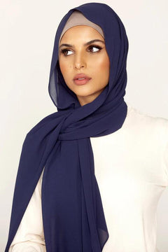 Georgette Hijab, in color Navy Blue. Girl wearing it with white top looking her right.