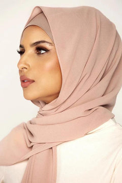 Georgette Hijab Online Pakistan, in khaki rose color. A woman wearing it with white top looking her right.