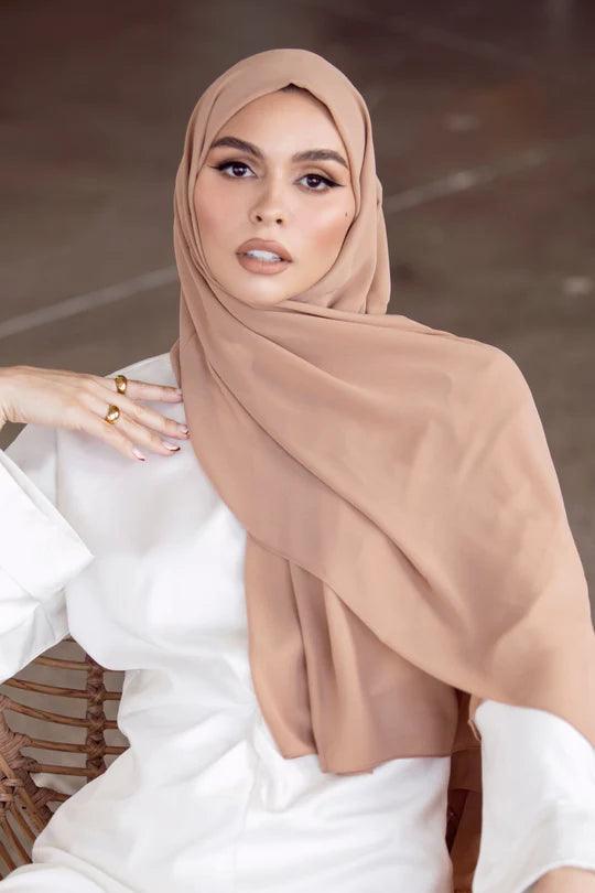 Girl styling on chair in Georgette Hijab in Beige, with white top looking her straight.