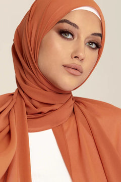 Georgette Hijab Online Pakistan, in coral bliss color . a women wearing it with white top looking her straihgt.