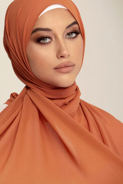 Georgette Hijab Online Pakistan, in coral bliss color . a women wearing it with white top looking her straight.