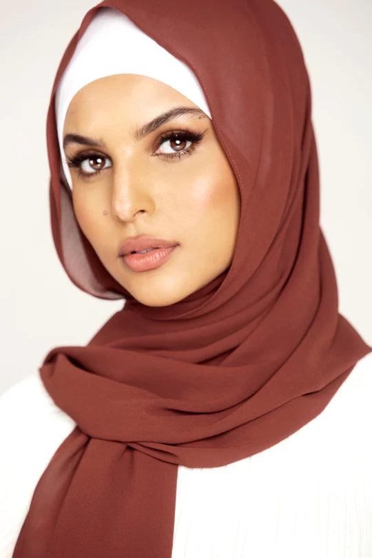 Georgette Hijab Online Pakistan, in sugar plum color. A woman wearing it with white top looking her right.