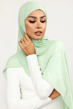 Georgette Hijab Online Pakistan, in mint green color. A woman wearing it with white top looking her left bottom.