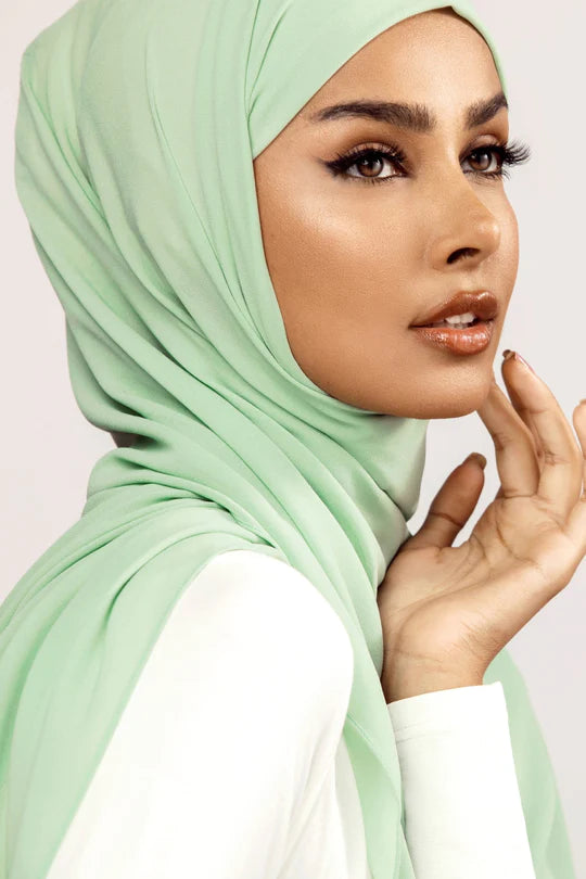 Georgette Hijab Online Pakistan, in mint green color. A woman wearing it with white top looking her right side profile.