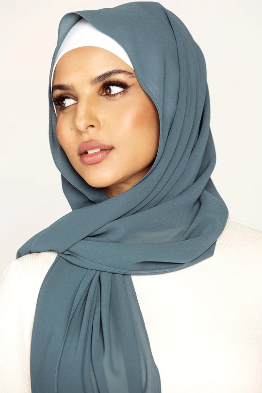 Georgette Hijab Online Pakistan, in YALE color . a women wearing it with white top looking her right.