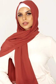 Georgette Hijab Online Pakistan, in rust color. A woman wearing it with white top looking her straight.