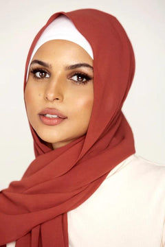 Georgette Hijab Online Pakistan, in rust color. A woman wearing it with white top looking her straight.