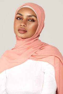 Georgette Hijab Online Pakistan, in soft peach color. A woman wearing it with white top looking her straight.