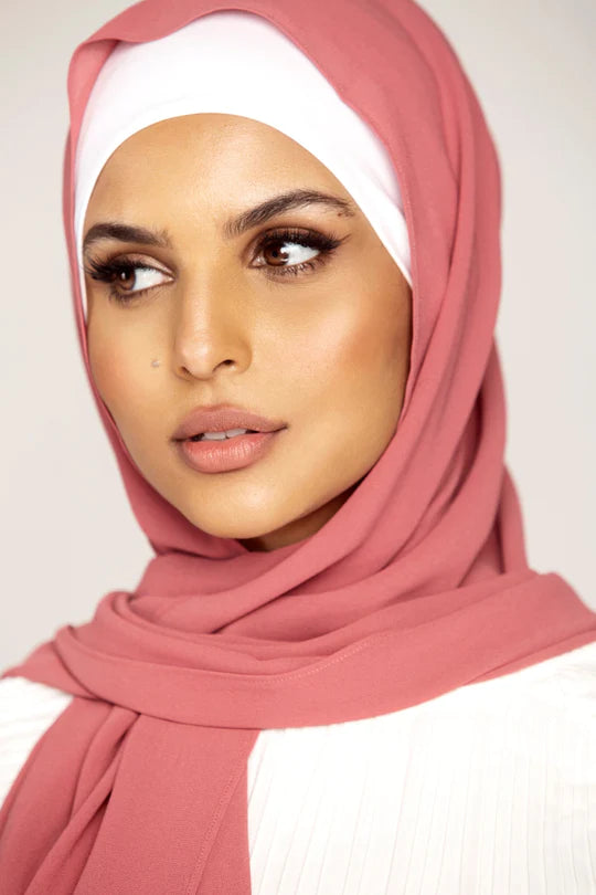 Georgette Hijab Online Pakistan, in pink berry color . a women wearing it with white top looking her right.