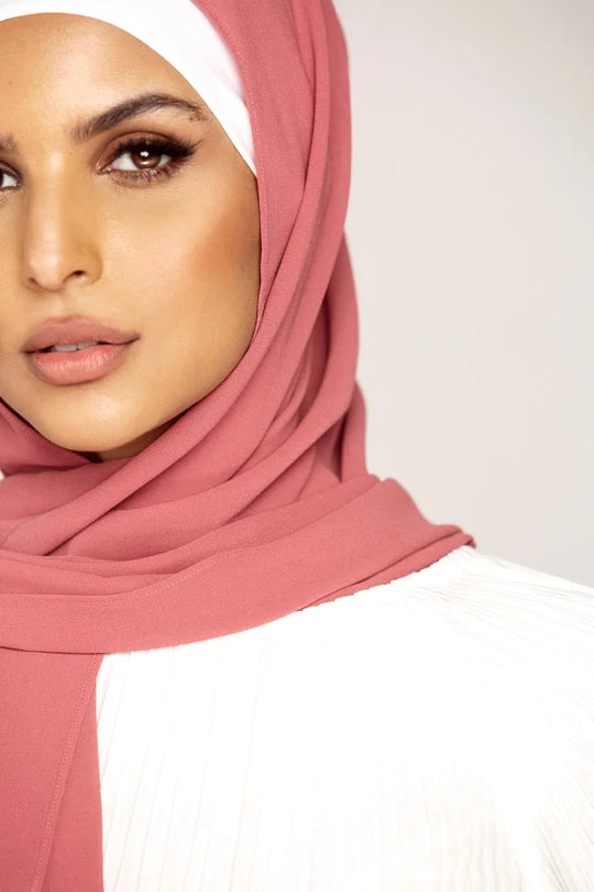 Georgette Hijab Online Pakistan, in pink berry color . a women wearing it with white top. Half profile.